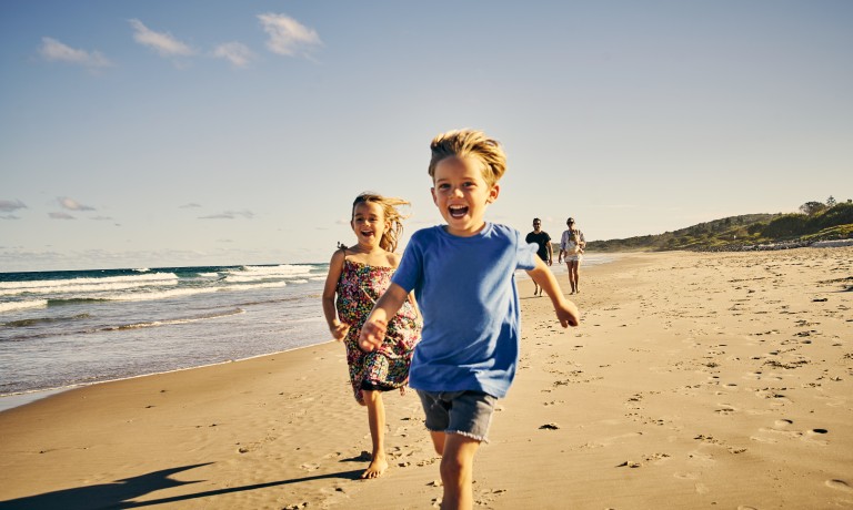 Lachende Kinder die am Strand langrennen