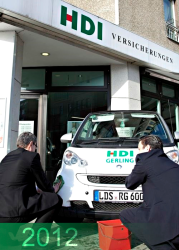 Weißer Smart mit HDI Logo vor einer HDI Versicherungsagentur