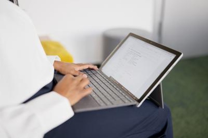 Ein Laptop steht auf einem Schoß und daran wird gearbeitet.