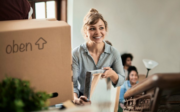 Frau mit Bilderrahmen in der Hand zieht um