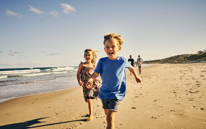 Lachende Kinder die am Strand langrennen