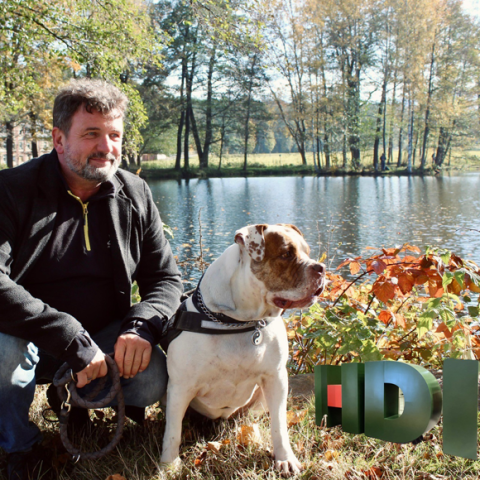 Tauber und Hund sitzten in der Natur und rechts unten sieht man das HDI Logo