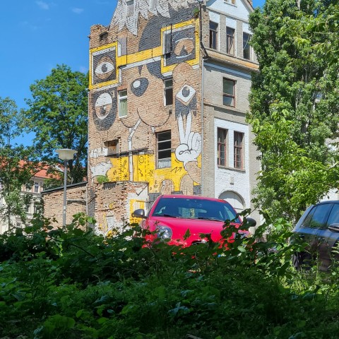 Auf einem Backsteinhaus wurde ein Gesicht gezeichnet, das das Symbol "Peace" zeigt