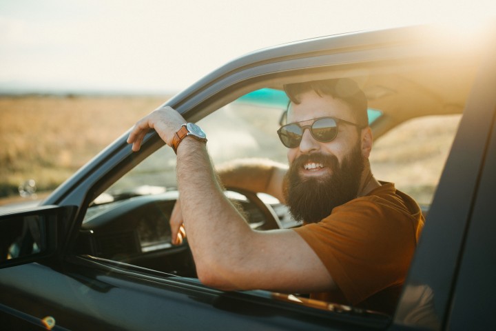 Man der lachend aus Autofenster rausguckt