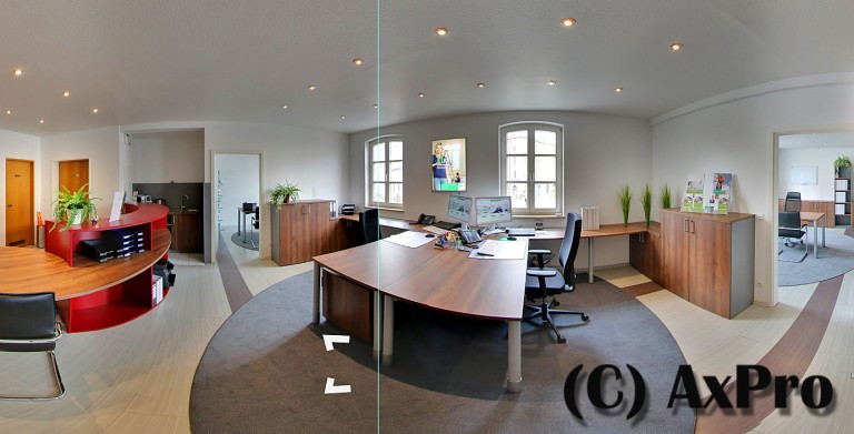 links ist ein brauner Schreibtich mit einem schwarzen Stuhl und einem PC, hinter dem Schreibtisch ist ein Fenster, rechts vor der Wand steht ein braunes Regal mit Flyer von der HDI Agentur. rechts ist ein Durchgang und dieser führt zu einem weiteren Büro, indem ein Tisch und Stühle stehen