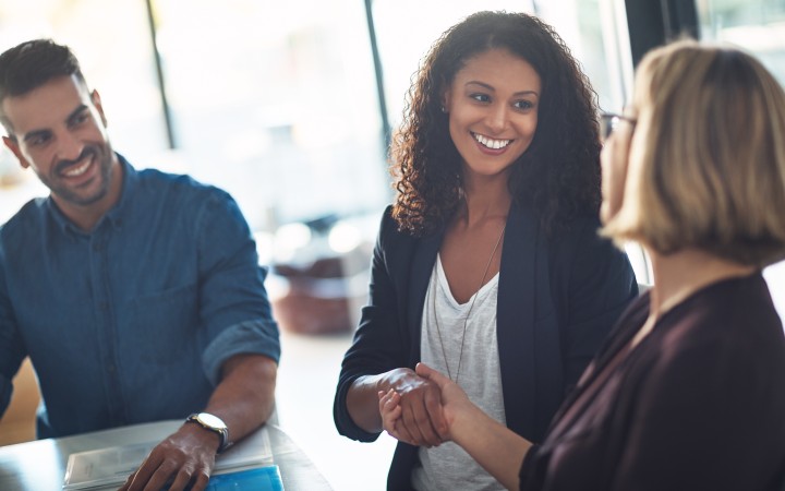 zwei Mitarbeiterinnen stehen sich gegenüber und schütteln sich die Hand