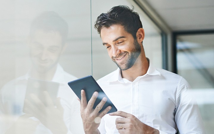 Mann mit einem Tablet in der Hand, auf das er drauf schaut.