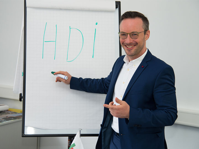 Andreas Jüngling steht vor einer Tafel mit einem Papier, auf dem Parpier steht in grün HDI