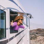 Eine Frau streckt ihren Oberkörper aus dem Wohnwagen.