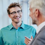 Der Mann lächelnd beim erklären eine Mann an, der mit dem Rücken zur Kamera steht. 