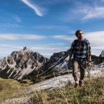 Ein Mann wandert auf einem Berg mit Steinen und Gras.