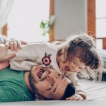 Vater und Kind die sich lachend auf dem Boden rollen