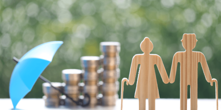 Ein Paar aus Pappe mit einem Schirmsteht im Vordergrund, hinter ihnen sind Münzen gestapelt.