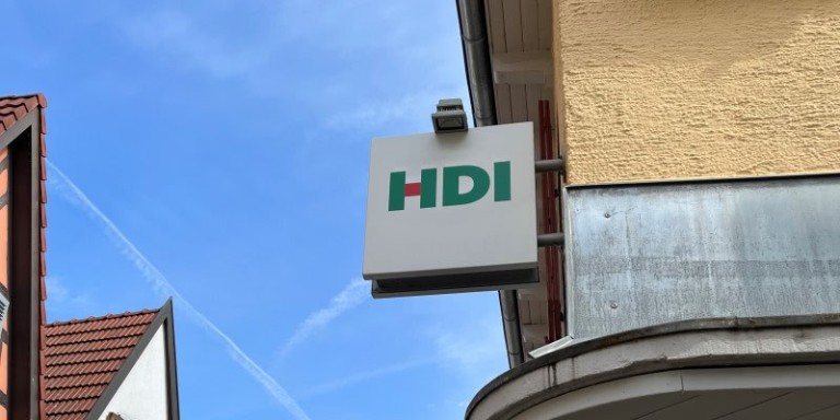 Man sieht das HDI Logo an einer Hauswand hängen.
