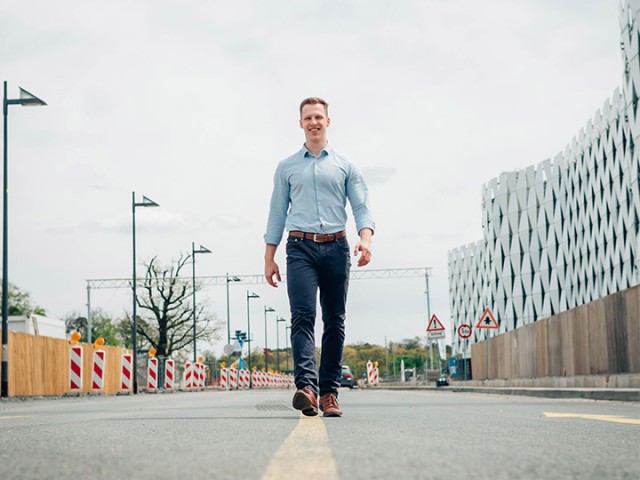 Bernhard Horn läuft auf einer Straße, im Hintergrund sind eine Baustelle und Verkehrszeichen erkennbar