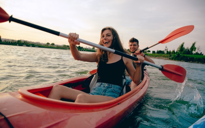 Zwei Personen die in Paddelboot sitzen und lachen