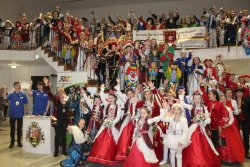 Menschen mit Kostümen stehen unten, auf einer Treppe und oben verteilt für das Foto.