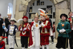 fünf Kinder, die verkleidet vor einem Steinbogen stehen mit einem Mikro