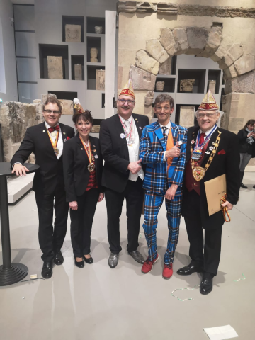 fünf Erwachsene, die verkleidet sind, stehen vor einem Steinbogen