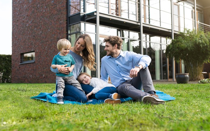 Eine glückliche Familie sitzt im Garten vor ihrem haus auf einer Decke