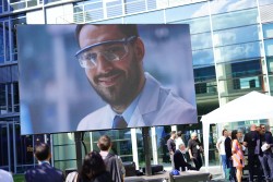 Bild von Leinwand beim Digital HUB Bonn. Auf der Leinwand ist ein Mann mit Schutzbrille zu sehen.