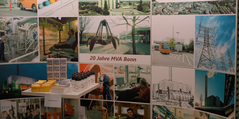 Bild von Mitarbeiter in gelber Warnweste und mit Schutzhelm. Er deutet auf Bildschirme mit Grafiken.