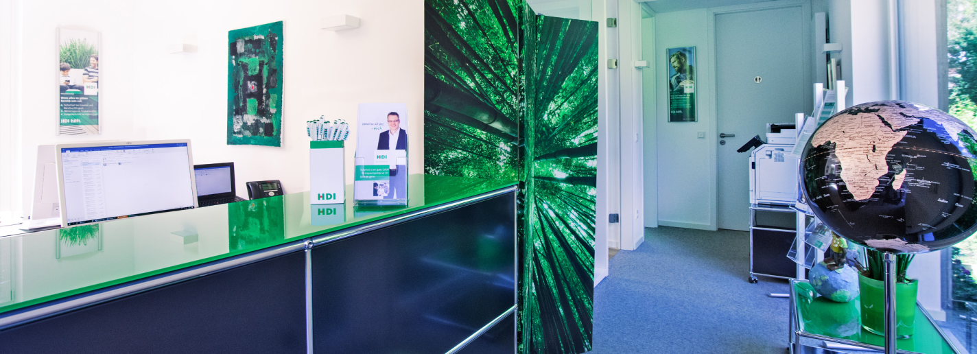 Tresen im Empfangsbereich der Agentur, dahinter stehen Bildaschirme. Rechts ist eine Weltkugel zu sehen