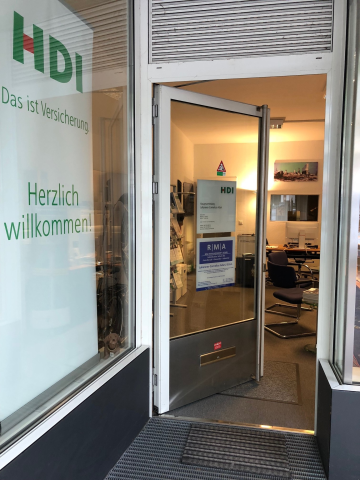 Man sieht die Eingangstur zur Agentur und mehrere Schilder mit dem HDI Logo.