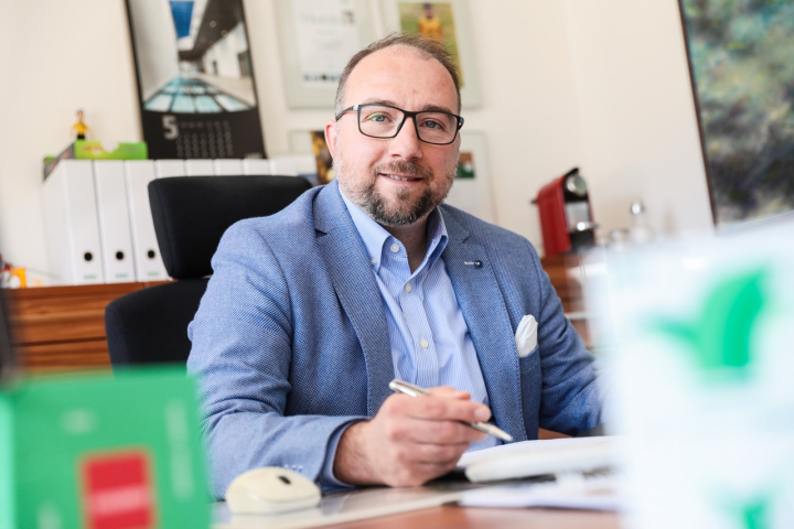 Karl Kramer am Schreibtisch und er hält ein Stift in der Hand