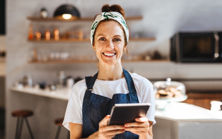 Frau mit Schürze und Tablet in der Hand 
