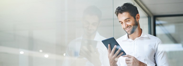 Mann mit einem Tablet in der Hand, auf das er drauf schaut.