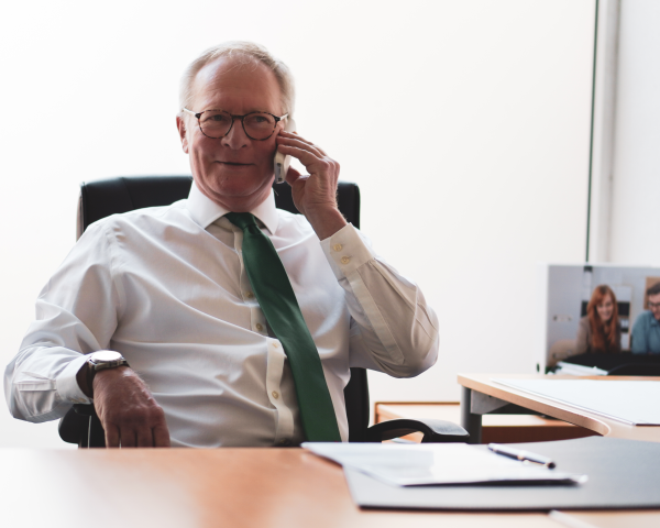 Michael Jansweid sitzt am Schreibtisch und telefoniert.