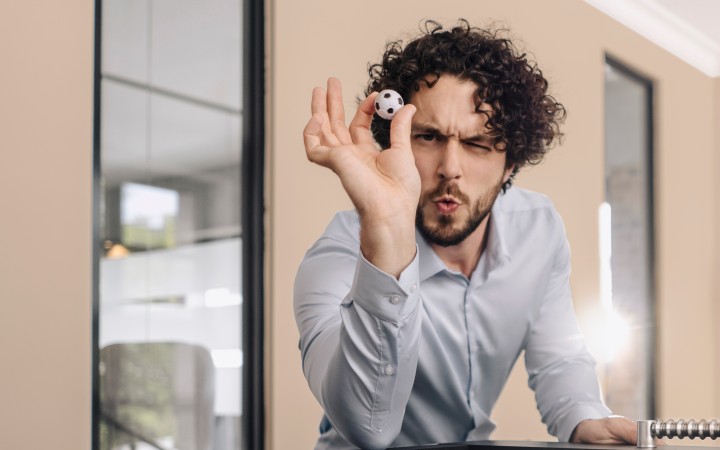 Mann wirft kleinen Fußball auf einen Tischfußballtisch 