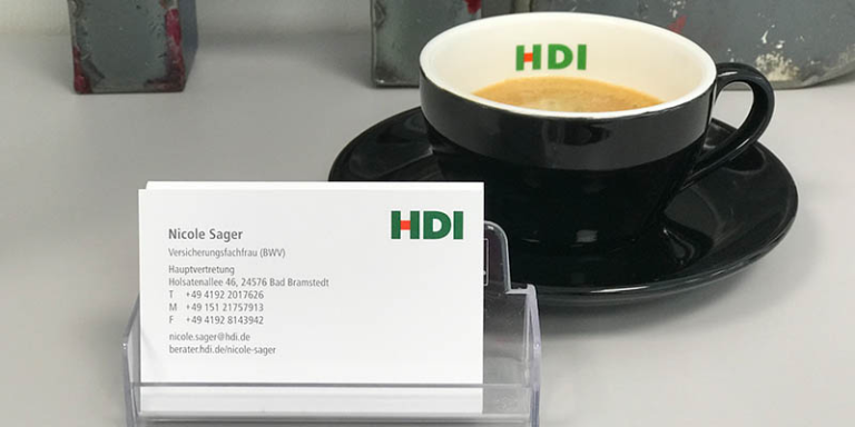 Kaffetasse mit HDI Logo sowie eine Visitenkarte von Nicole Sager