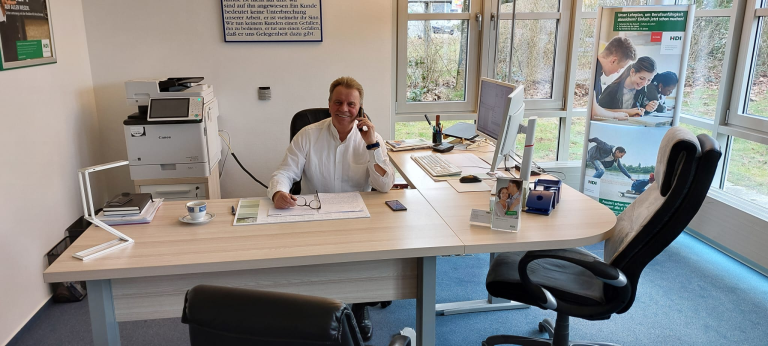 Norbert Redöhl sitzt am Schreibtisch und telefoniert 