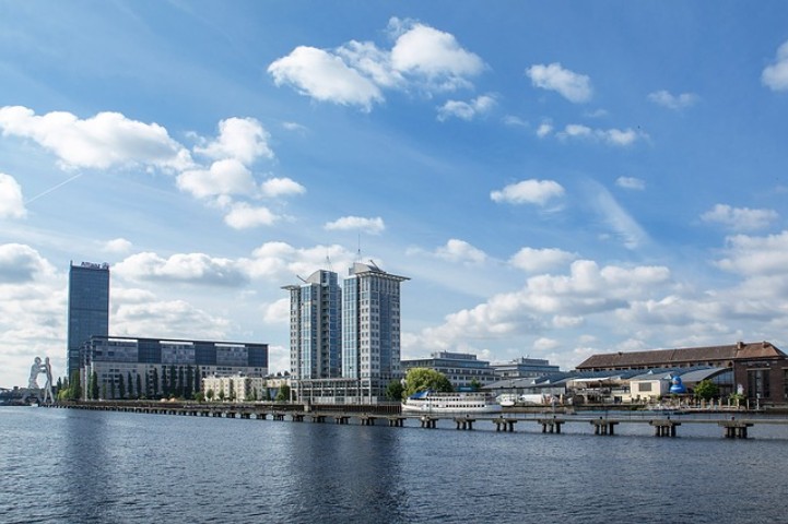 Stadt mit blauem Wasser, Brücke, Wolkenkratzer, Häuser, Bäumen und einen blauen Himmel
