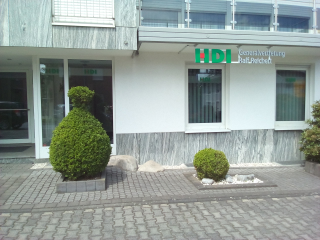 weißes Haus der HDI Agentur vor dem drei Büsche stehen