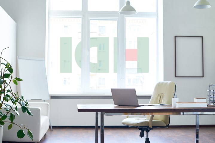 Leeres HDI Büro. Man sieht einen Schreibtisch mit Laptop, ein weißes Sofa, und eine Fensterfront auf der spiegelverkehrt das HDI Logo zu sehen ist