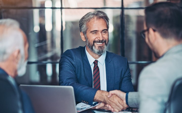 Drei Männer, zwei der Männer geben sich die Hand