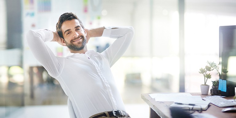 Ein Mann, der sich zurücklehnt und die Arme hinter dem Kopf verschränkt.