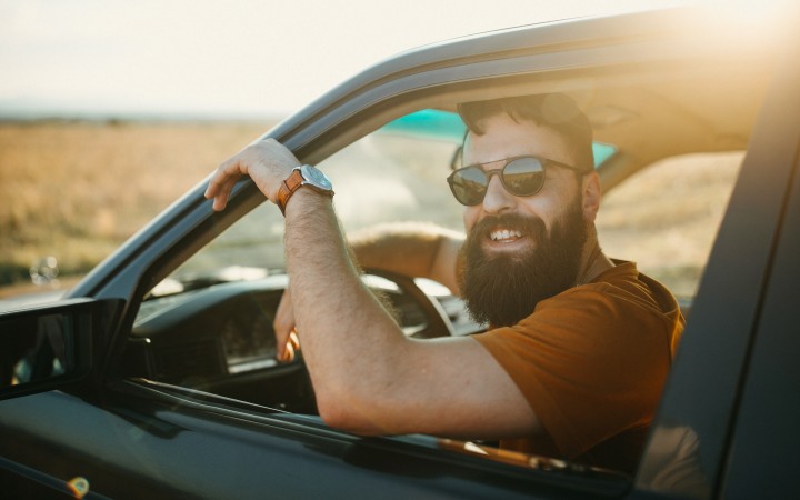Man der lachend aus Autofenster rausguckt