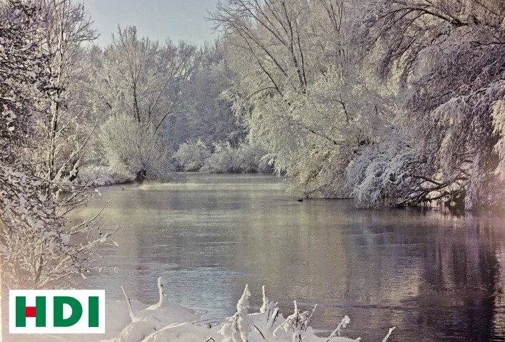 Fluss gesäumt von Bäumen, die von Frost überzogen sind. In der unteren linken Ecke ist das HDI-Logo.