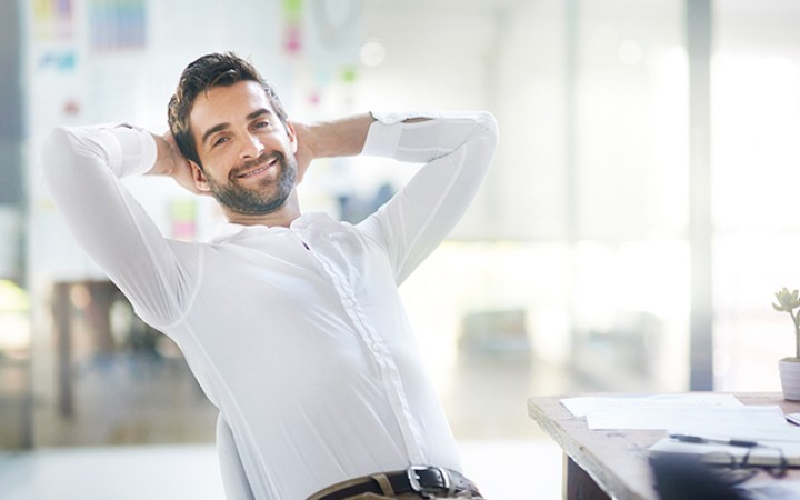 Ein Mann, der sich zurücklehnt und die Arme hinter dem Kopf verschränkt.