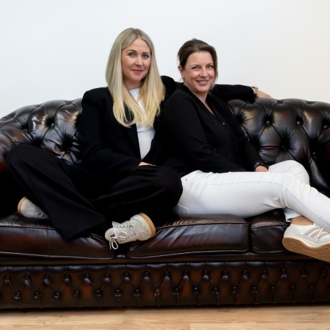 Eberhardt und Janowski sitzen auf einem Sofa