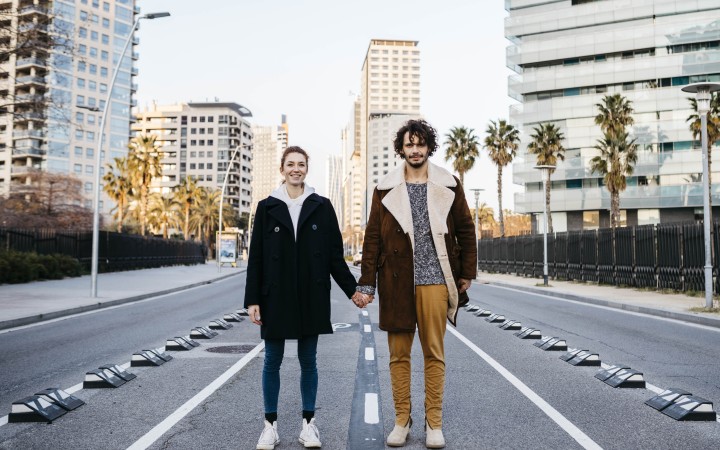 Hände haltendes Pärchen steht auf der Straße
