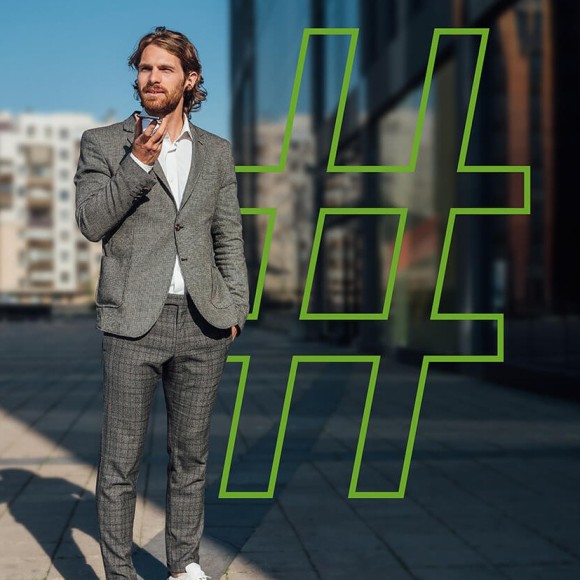 Ein Mann im Anzug steht draußen und schaut auf sein Smartphone. Im Hintergrund ist ein großes Hashtag-Symbol. 