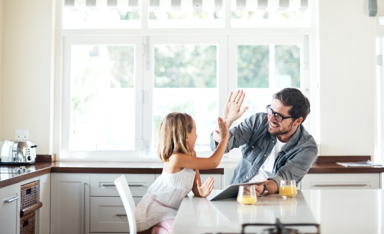 Vater und Tochter in der Küche, beide lachen und geben sich ein High-Five
