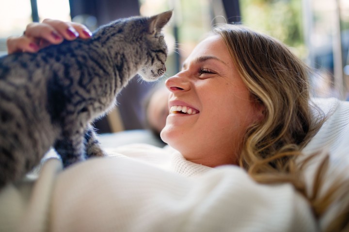 Lächelnde Frau mit Katze auf dem Arm