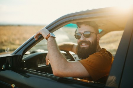 Man der lachend aus Autofenster rausguckt