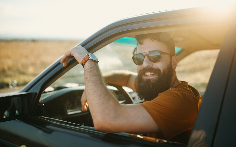 Man der lachend aus Autofenster rausguckt